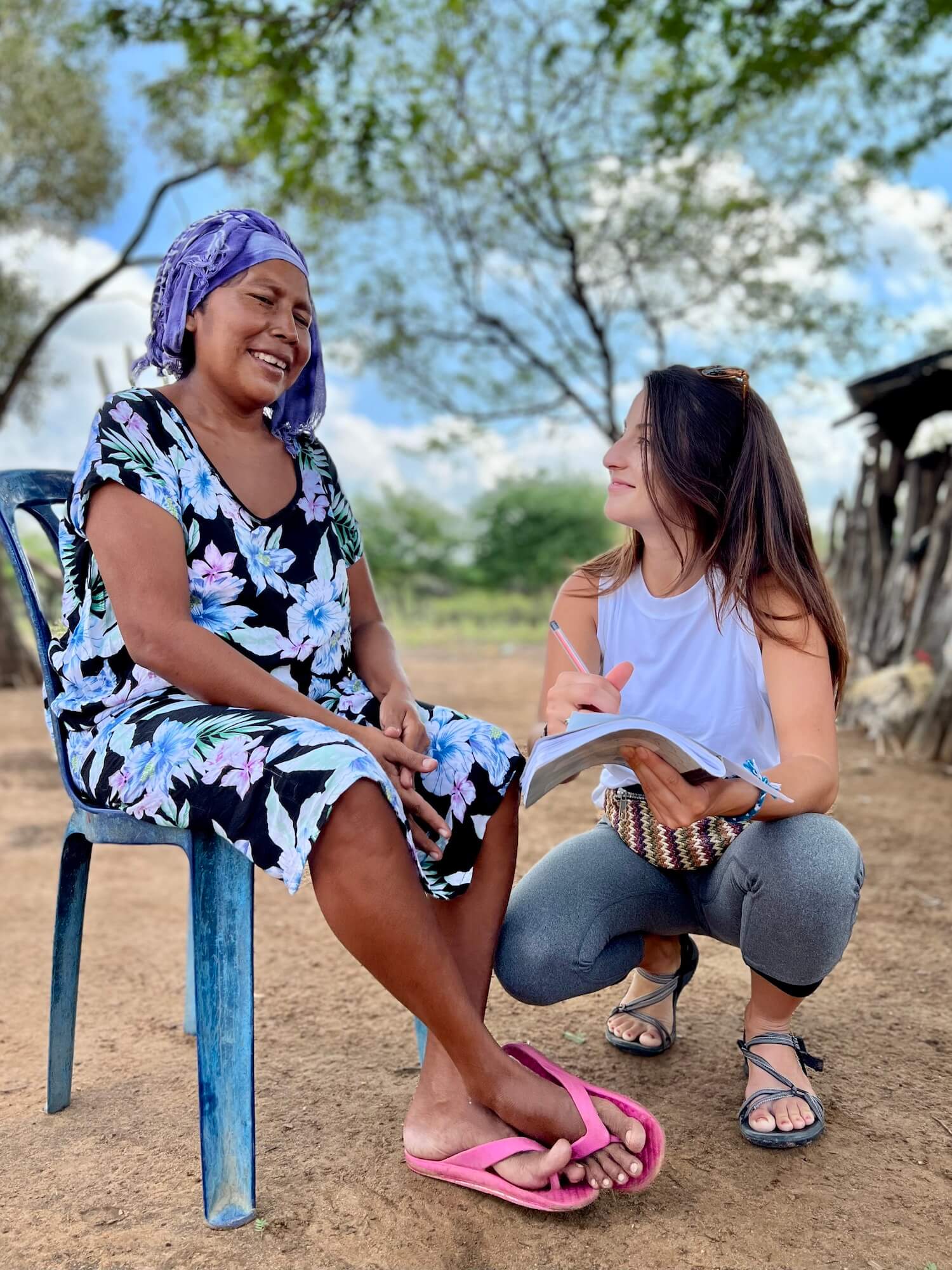 girl crouching next to a Wayuu women conducting a community interview
