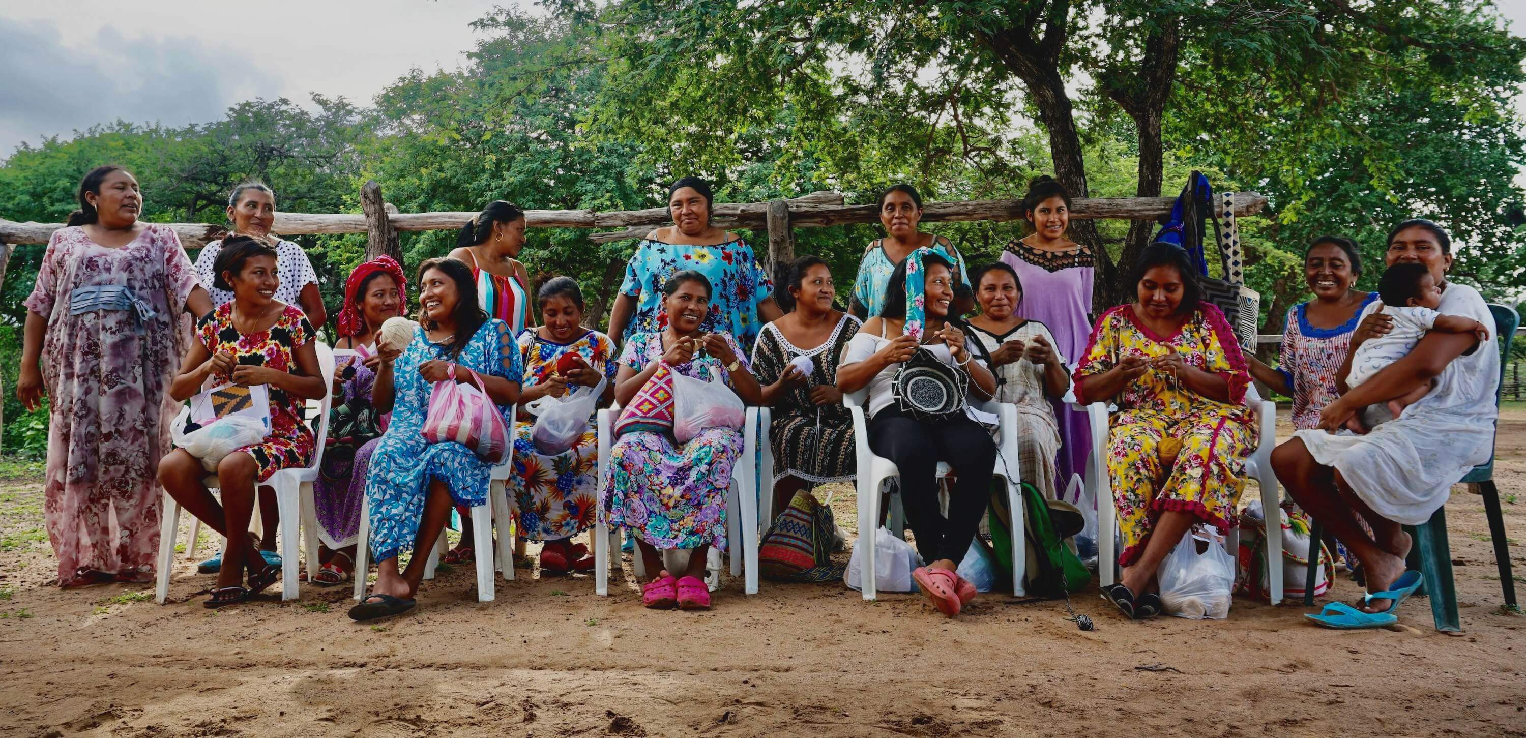 Group of Wayuu women smiling and crocheting crossbody mochilas