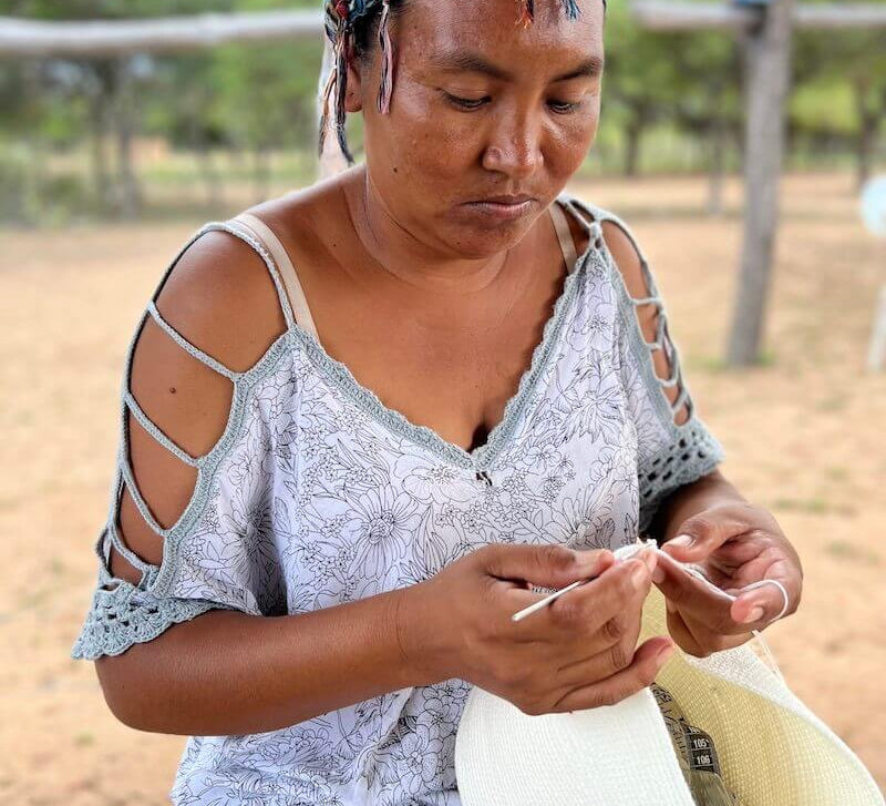 Wayuu women wearing a headscarf and "manta" dress crocheting a crossbody mochila