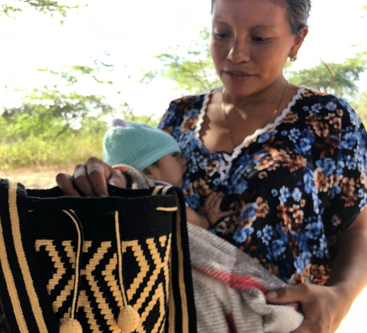 Young Wayuu mother with her baby and crochet crossbody mochila bag