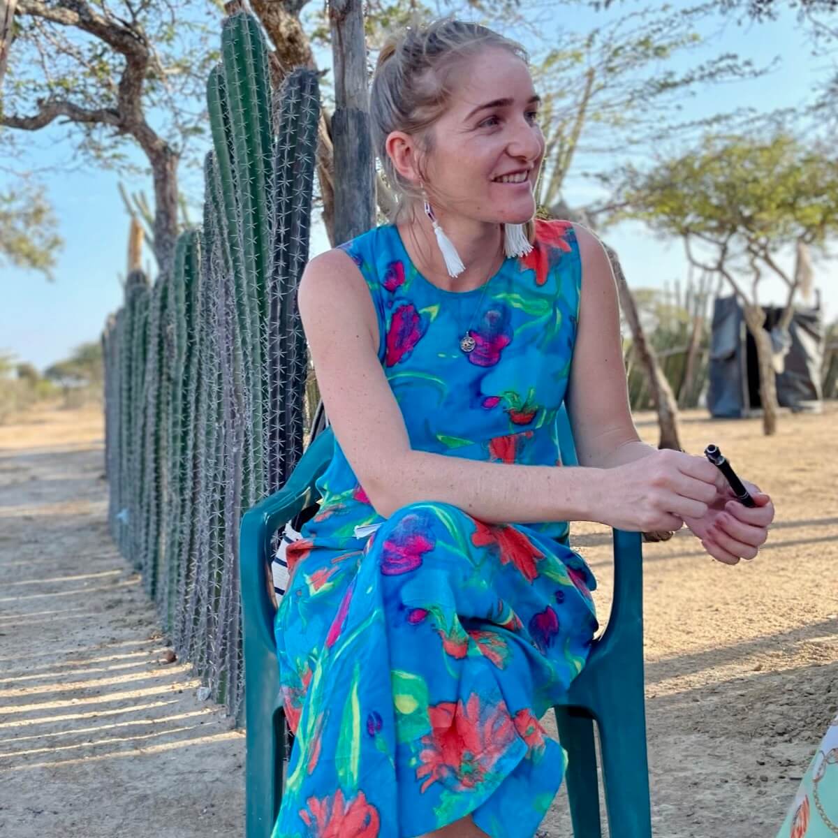 Young woman sitting in front of a cactus fence in an Indigenous village
