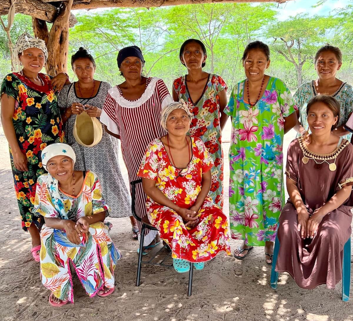 Group of Wayuu women smiling under a traditional "enramada"