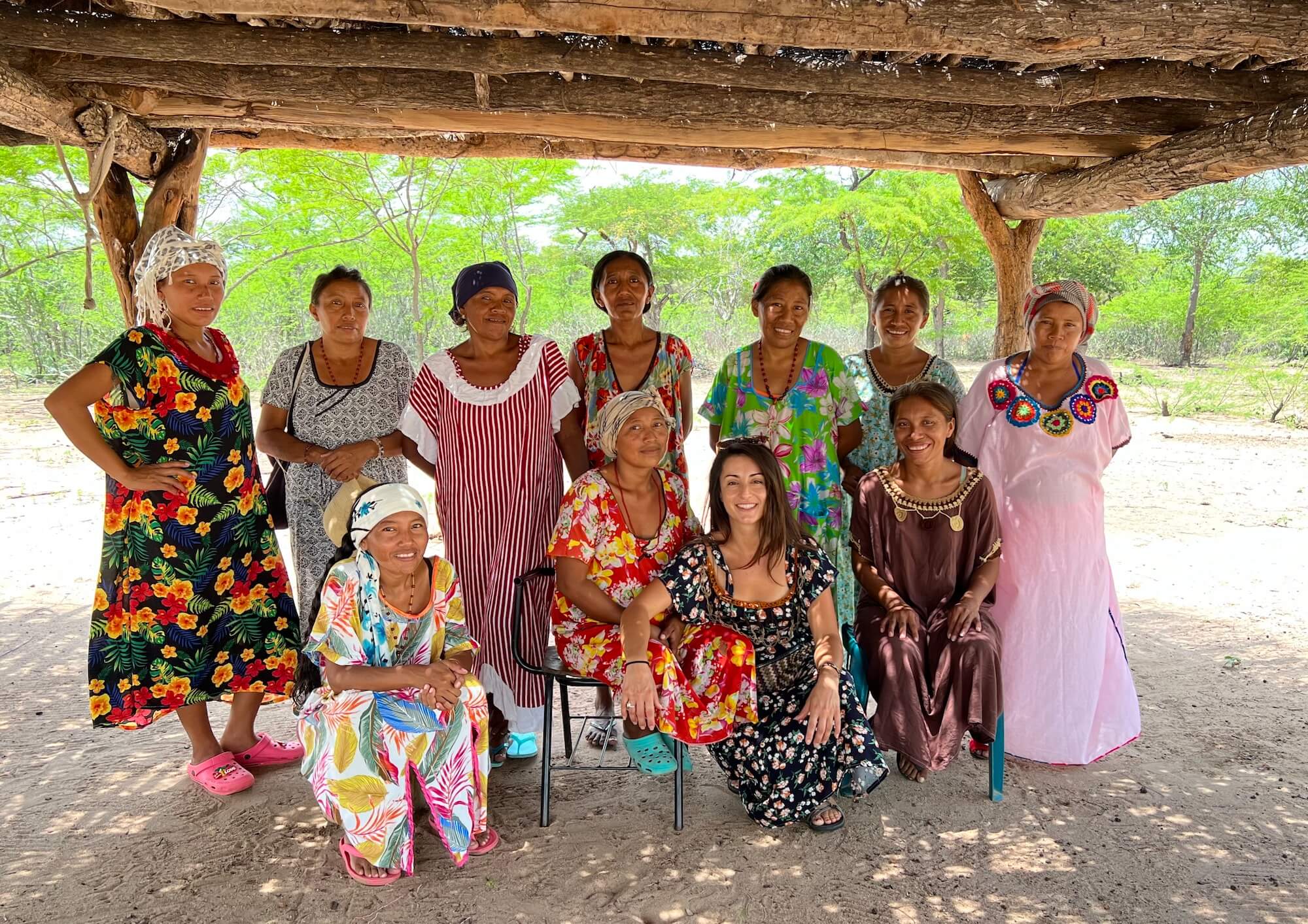 Group of Wayuu women and cofounder smiling in a traditional Indigenous "rancheria"